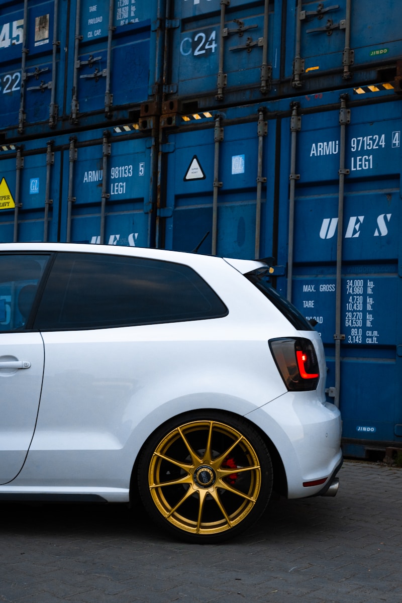 a white car parked in front of a blue container